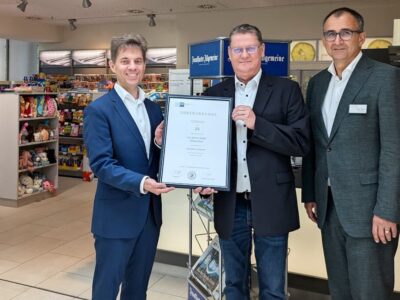 Simon Suffa, Büroleiter der IHK Schweinfurt überreichte Volker Röder, Geschäftsführer Leo-Service (Bildmitte) und Jürgen Winter (Geschäftsführer Leo Service und Leopoldina-Krankenhaus) vor dem durch die Servicegesellschaf betriebenen Leo-Shop die Urkunde zum 25-jährigen Bestehen. Foto: Julia Schüler