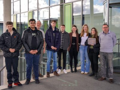 Hansjörg Rüthel, Betreuer der Schülerzeitung am Gymnasium Veitshöchheim (3. v. l.), und Michael Rott, Dozent und Betreuer der Studierenden aus dem Fachbereich E-Commerce (re.) freuen sich mit Teilnehmenden des P-Seminars sowie Studierenden der THWS über das gelungene Projekt (Foto: THWS/Niko Wörtmann)