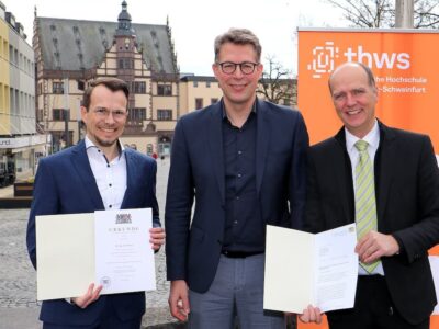 Markus Blume, Bayerischer Staatsminister für Wissenschaft und Kunst (Mitte), übergibt Prof. Dr. Jean Meyer (li.) auf dem Schweinfurter Marktplatz die Ernennungsurkunde zum neuen Präsidenten der THWS. Der scheidende Präsident Prof. Dr. Dr. h. c. Robert Grebner erhielt ein Dankesschreiben zur Beendigung seiner Amtszeit (Foto: THWS/Eva Kaupp)