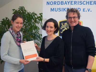 Dr. Laura Blauth von der THWS übergab Monika Feldmeier und Gerhard Cäsar vom Kooperationspartner Nordbayerischer Musikbund (NBMB) die fertige Handreichung (Foto: NBMB/Gerhard Cäsar)