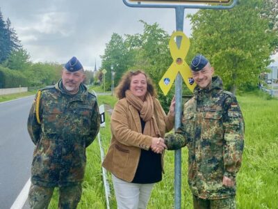 Unser Foto zeigt Sommerachs Erste Bürgermeisterin Elisabeth Drescher (Mitte) mit Major Alexander Kühn (rechts) und Oberstabsfeldwebel Frank Michael Kohler (links) vom Partnerbataillon, dem 6. Logistikbataillon 467, mit der gelben Schleife, die nun am Ortseingang von Sommerach hängt und die Verbundenheit und Solidarität symbolisiert. Foto: Gemeinde Sommerach