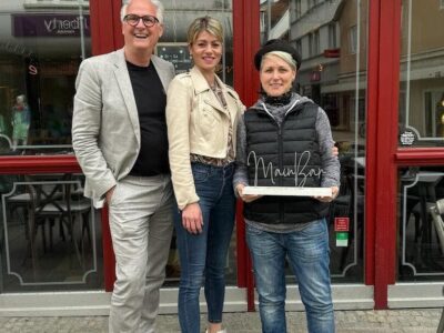 Die Mainbar-Inhaberin Ramona Krines (Mitte) veranstaltet am 27. April bei freiem Eintritt ein Weinfest für einen guten Zweck. Ein Teil des Erlöses geht an die Schweinfurter Kindertafel e.V. und sie wird bei der Umsetzung des Weinfestes unterstützt von den beiden Botschaftern der Kindertafel Steffi List (rechts) und Peter Kruse (links). Foto: Frieda Siegel