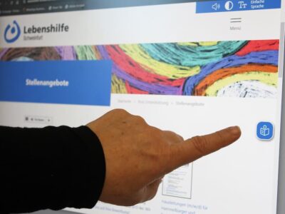 (Foto: Reto Glemser): Übersetzung per Mausklick für mehr Barrierefreiheit: Das blaue Feld mit dem weißen Lese-Symbol ziert seit Kurzem den rechten Bildschirmrand aller Seiten des Internetauftritts der Lebenshilfe Schweinfurt. Klickt man auf das Feld, übersetzt ein KI-Tool in Echtzeit den kompletten Text der Seite in Einfache Sprache.