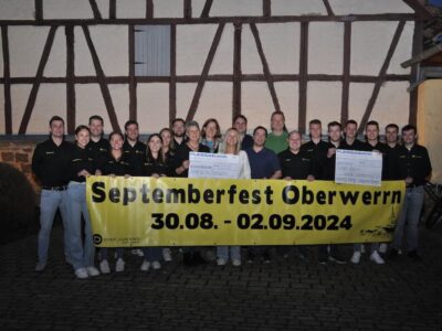 Tobias Wiederer und Kirsten Nicklaus vom Kindergarten Oberwerrn nehmen den Scheck von der Dorfjugend Oberwerrn entgegen. Insgesamt 10.500 € konnte die Dorfjugend als Erlös vom Septemberfest 2024 an den Kindergarten und an KioNet Bayern spenden.