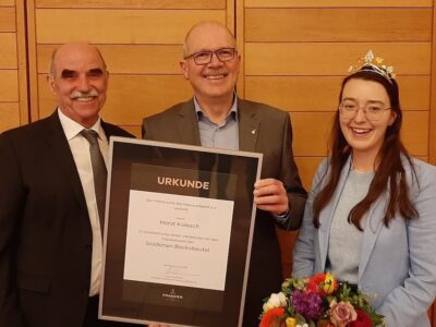 Präsident Artur Steinmann, Horst Kolesch und die 66. Fränkische Weinkönigin Lisa Lehritter (v. l. n. r.) mit der Verleihungsurkunde des Goldenen Bocksbeutels. Foto: Stephan Schmidt/Fränkischer Weinbauverband e. V.