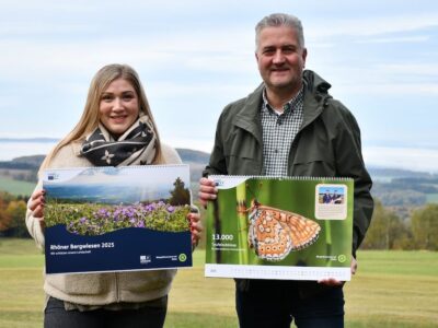 LIFE-Projektleiterin Katharina Bach und Torsten Raab, Leiter der Hessischen Verwaltungsstelle des UNESCO-Biosphärenreservates Rhön, präsentieren den neuen Bergwiesen-Wandkalender. Foto: Lea Hohmann