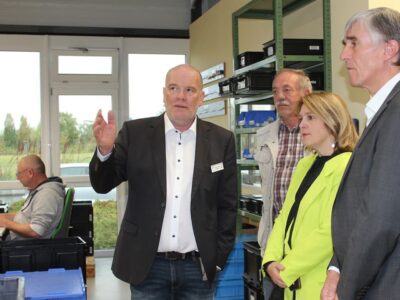Werkstattleiter Jürgen Hergenröder (1. v. l.) zeigt im Beisein des stellvertretenden Lebenshilfe-Vorstands Konrad Schneider (2. v. l.), der CSU-Landtagsabgeordneten Martina Gießübel (3. v. l.) und dem stellvertretenden Landrat Thomas Vizl die verschiedenen Werkstatt-Arbeitsbereiche. Zudem macht er darauf aufmerksam, dass alle Arbeitsschritte, die aufgrund ihrer Lautstärke die Werkstattmitarbeiter belasten, in einem separaten Raum eingefasst sind.